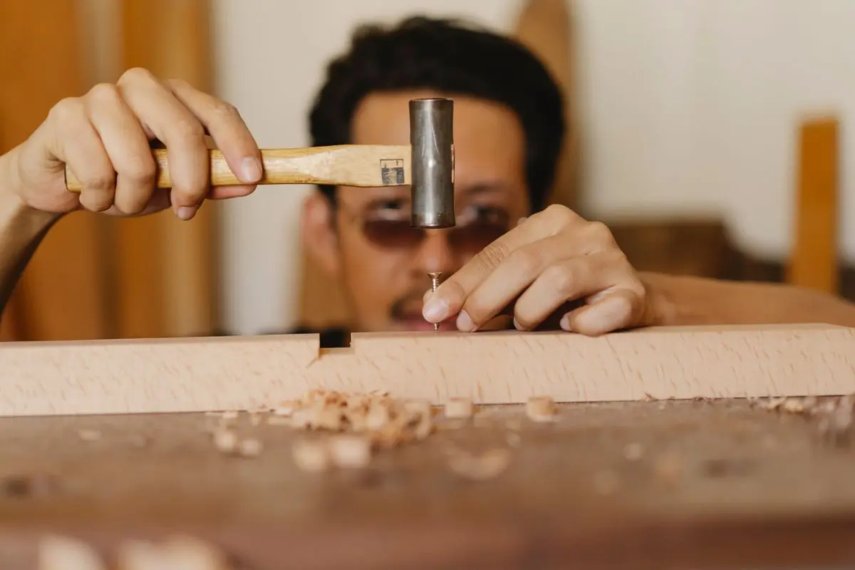 A joiner nailing a piece of hardwood in the workshop