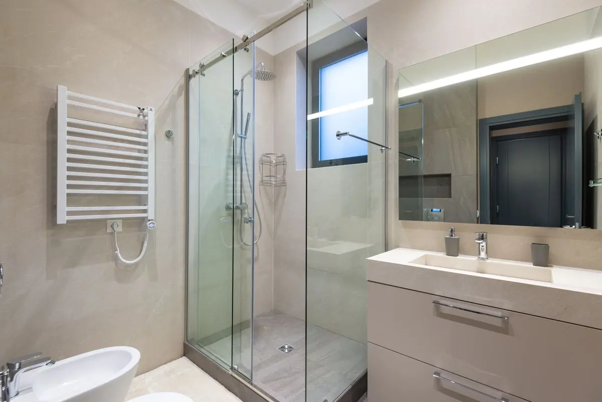 A finished bathroom with a glass shower and tiled walls