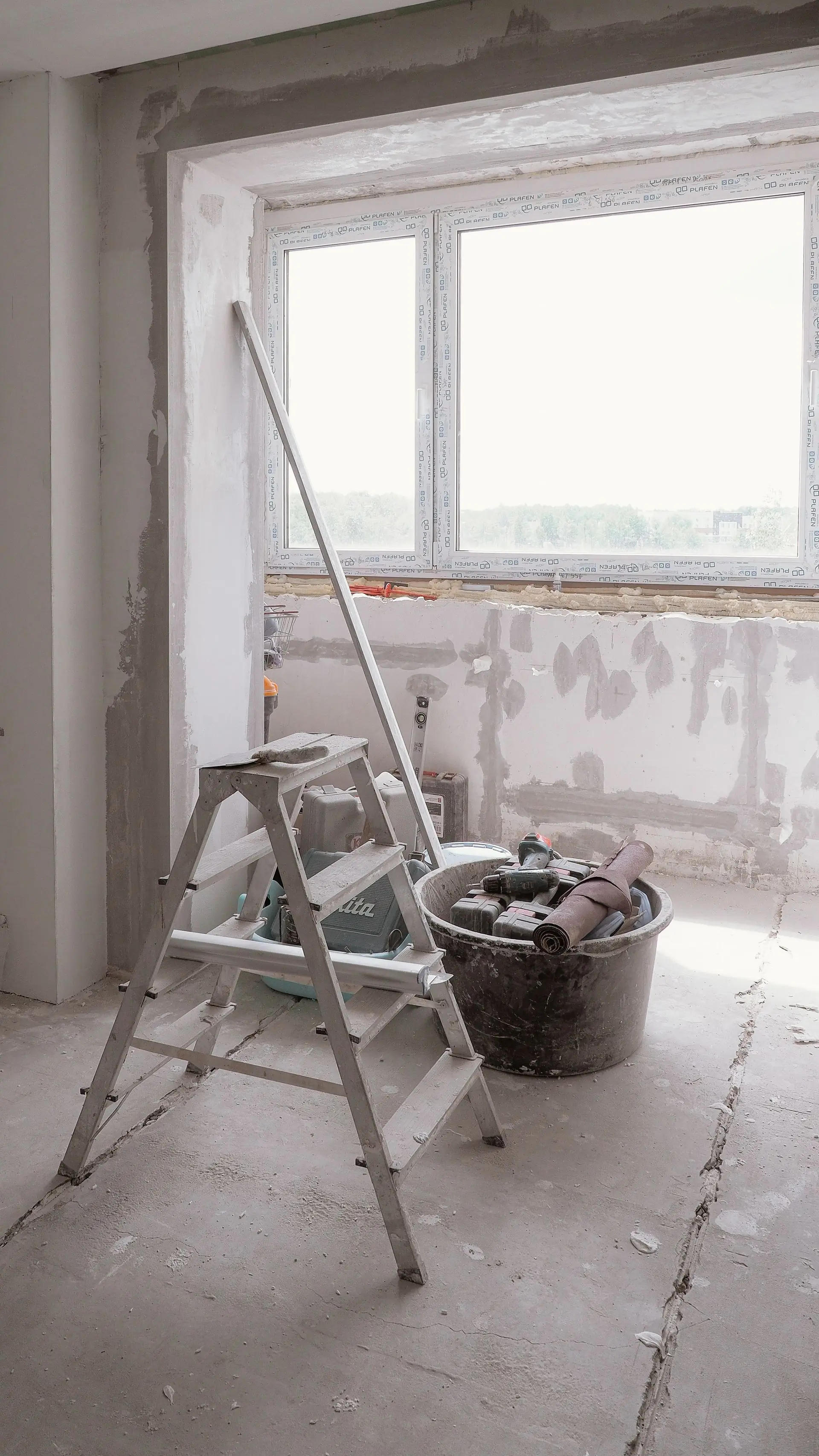 A room mid-renovation with a ladder and tools on the floor