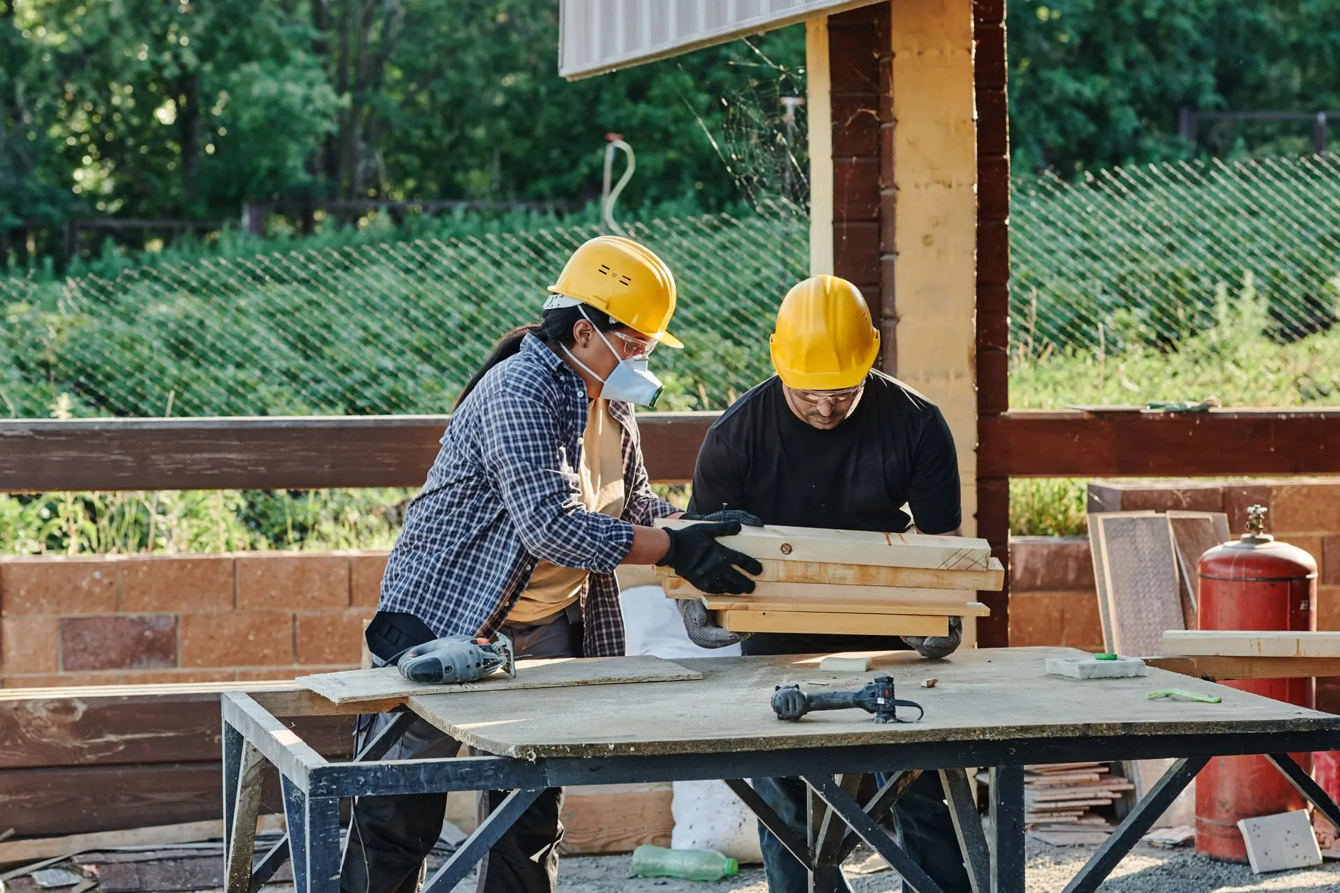 Two of the crew cutting timber at a bench in the yard