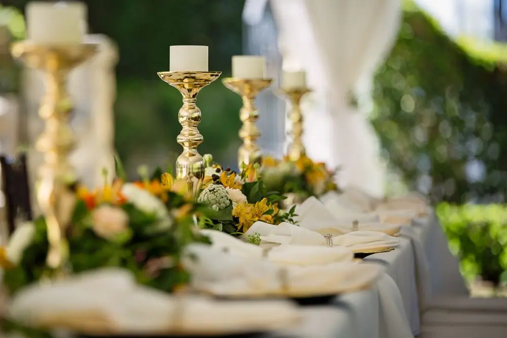 Tall gilded candlesticks and greenery running the length of a dressed table