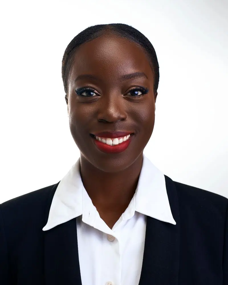 Efua Boateng in a dark jacket and white shirt against a pale background