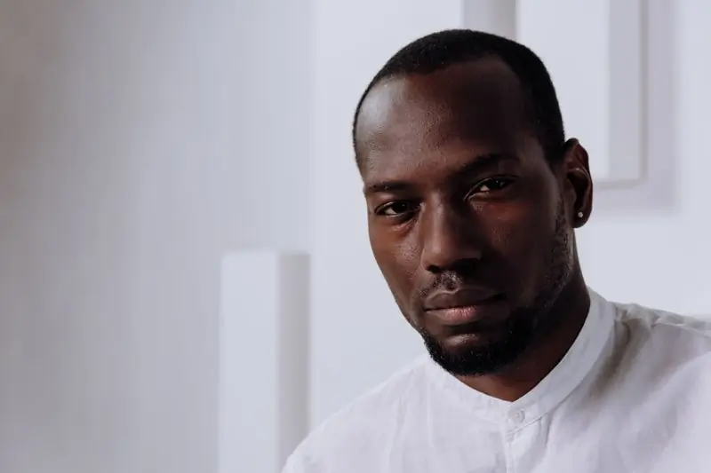 Kofi Amankwah in a white shirt, photographed close against a pale wall