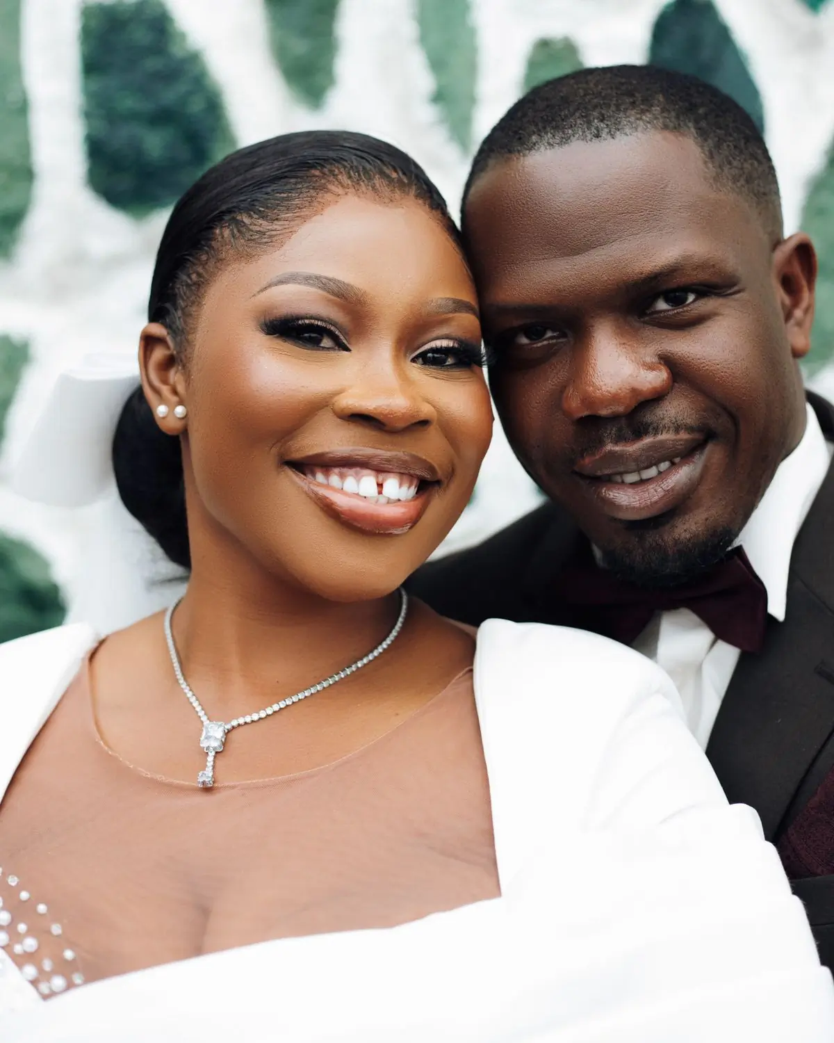 A smiling couple photographed cheek to cheek on their wedding day