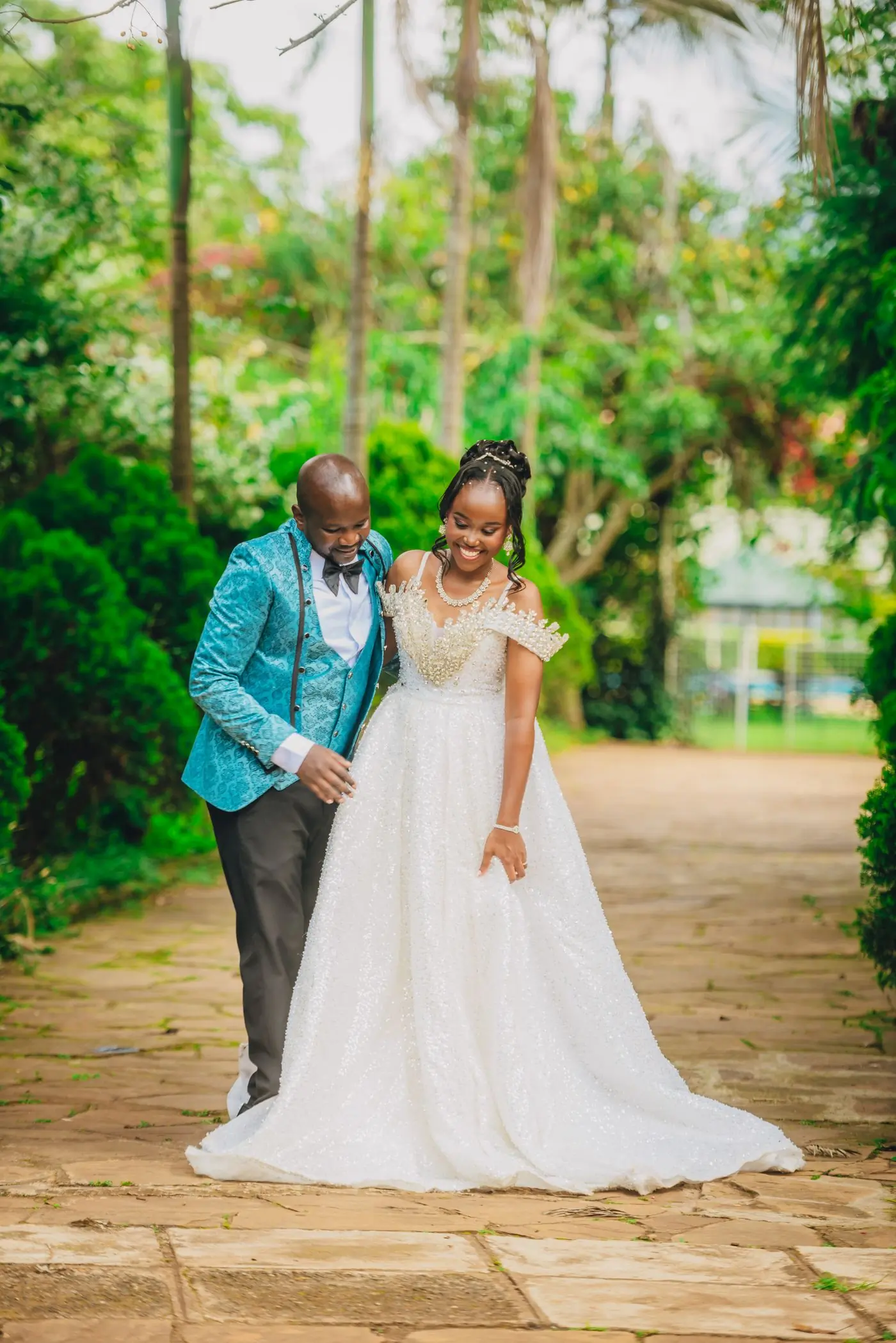 A bride and groom walking through a garden during their celebration