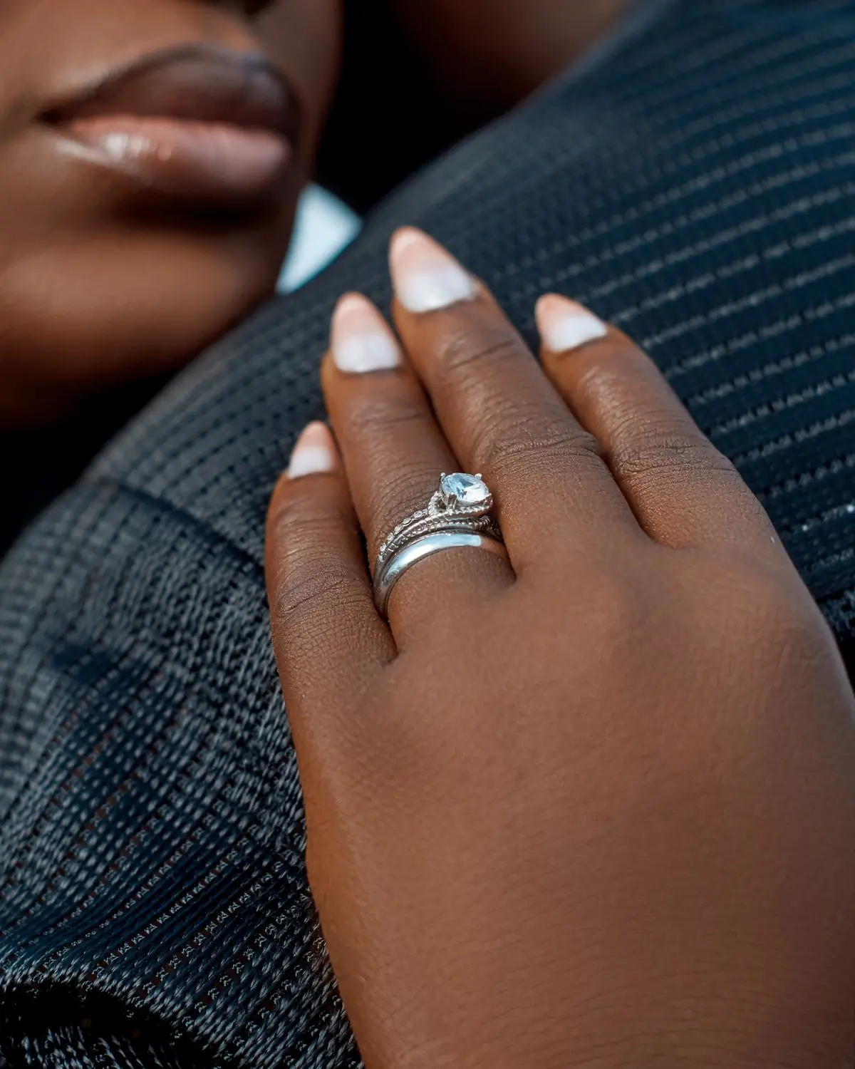 A bride's hand resting on her husband's shoulder, the ring in close-up