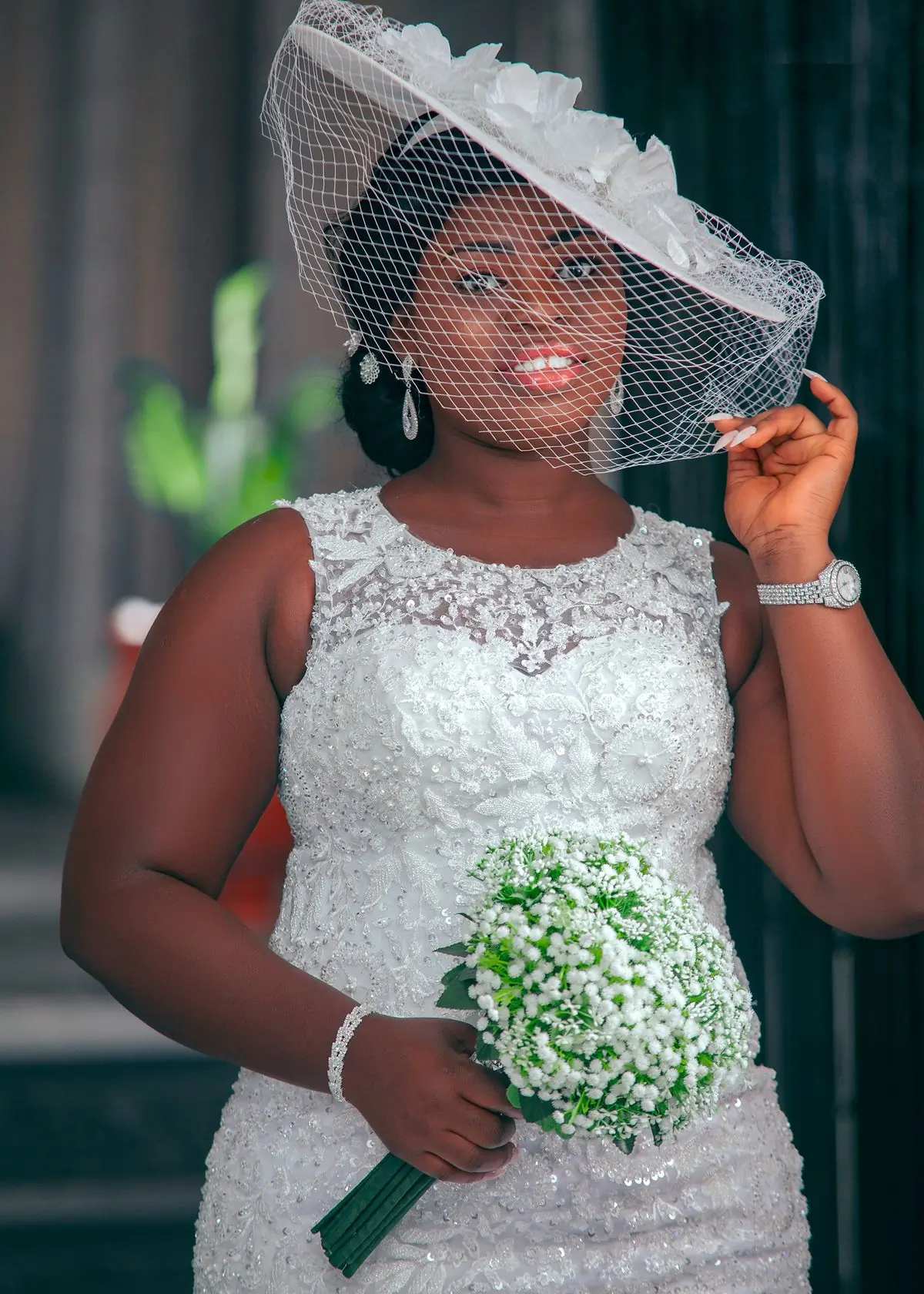 A bride in a veiled hat holding a bouquet, photographed in soft light