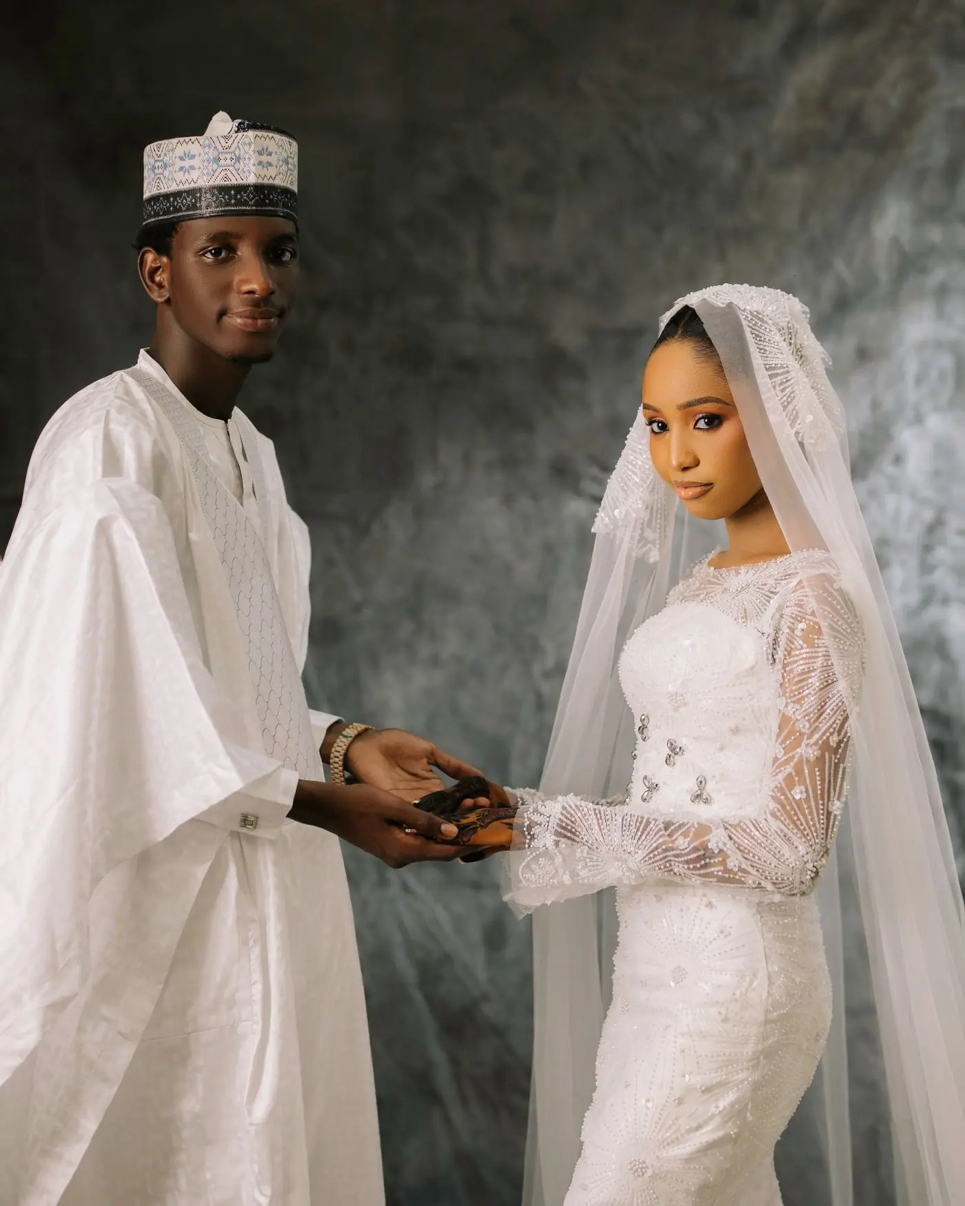 A bride and groom holding hands, the bride's veil across her shoulder