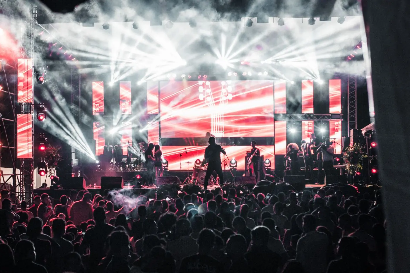 A band mid-set on a red-lit stage with the crowd close in front of them
