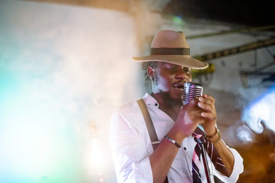 A singer in a brimmed hat at a vintage ribbon microphone