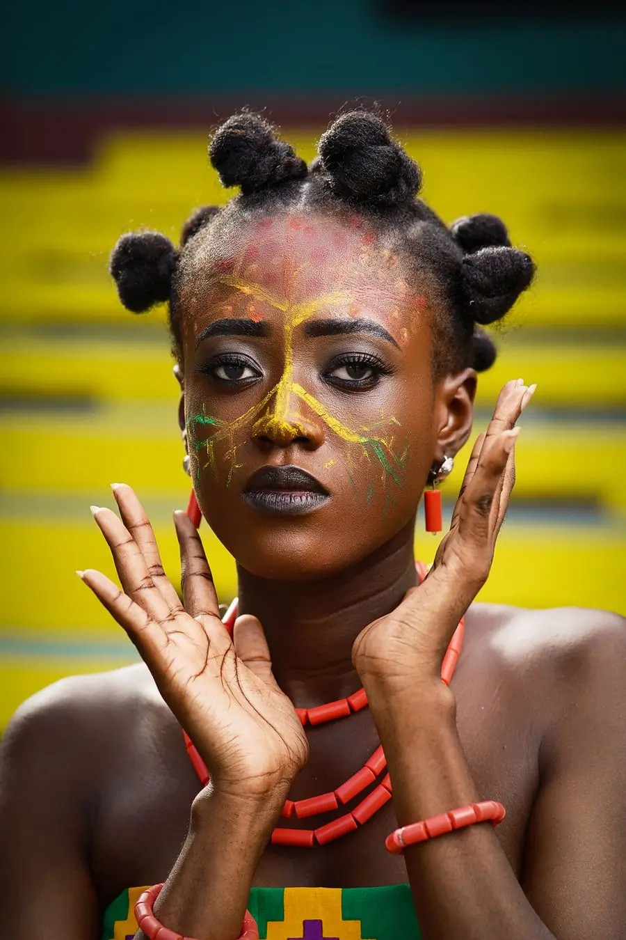 A performer in gold and green face paint against a yellow backdrop
