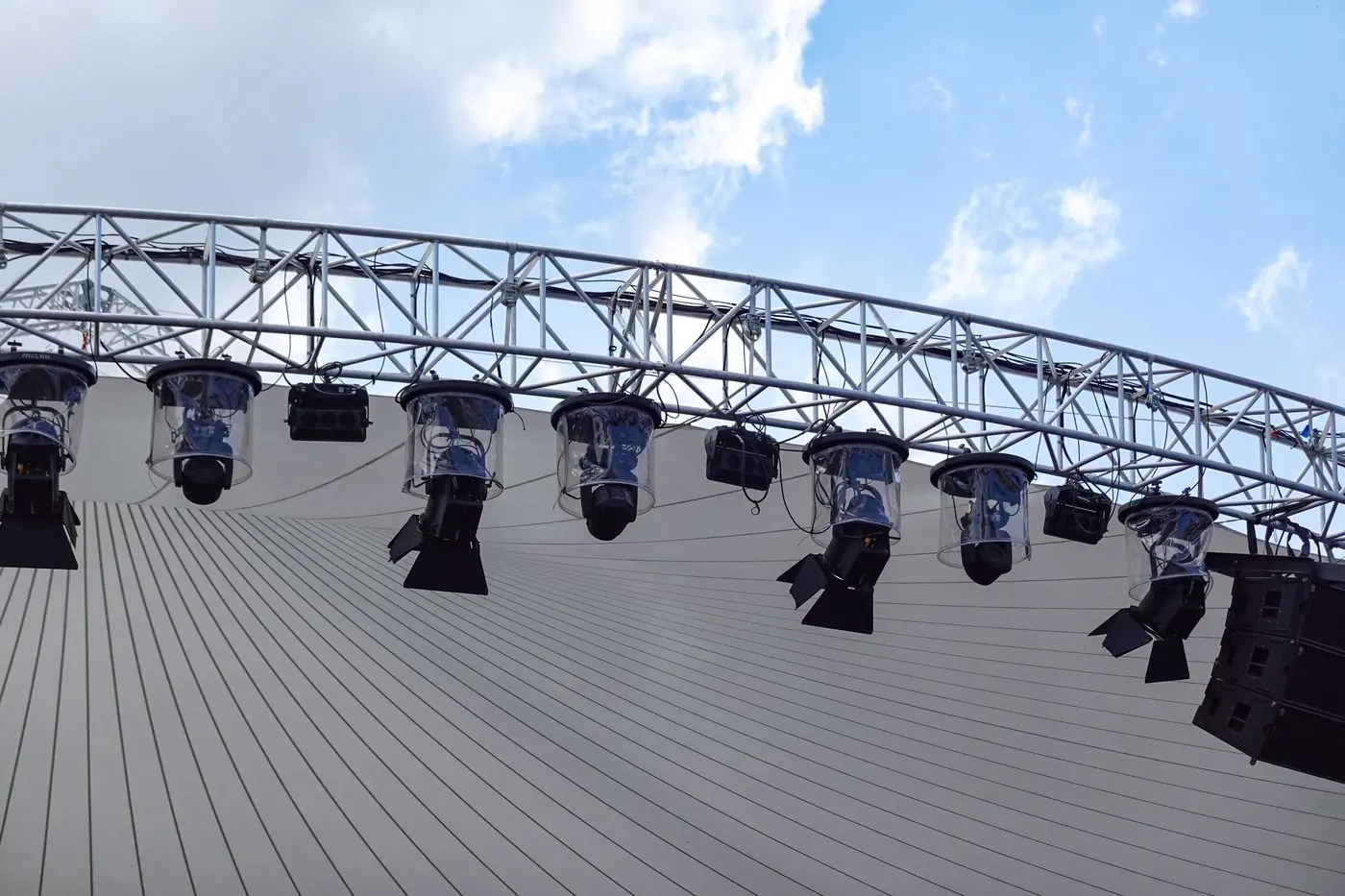 A lighting truss and moving heads against a blue sky