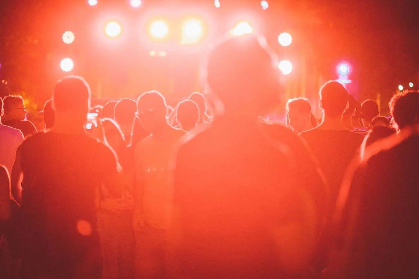 A crowd in silhouette against deep red stage lighting