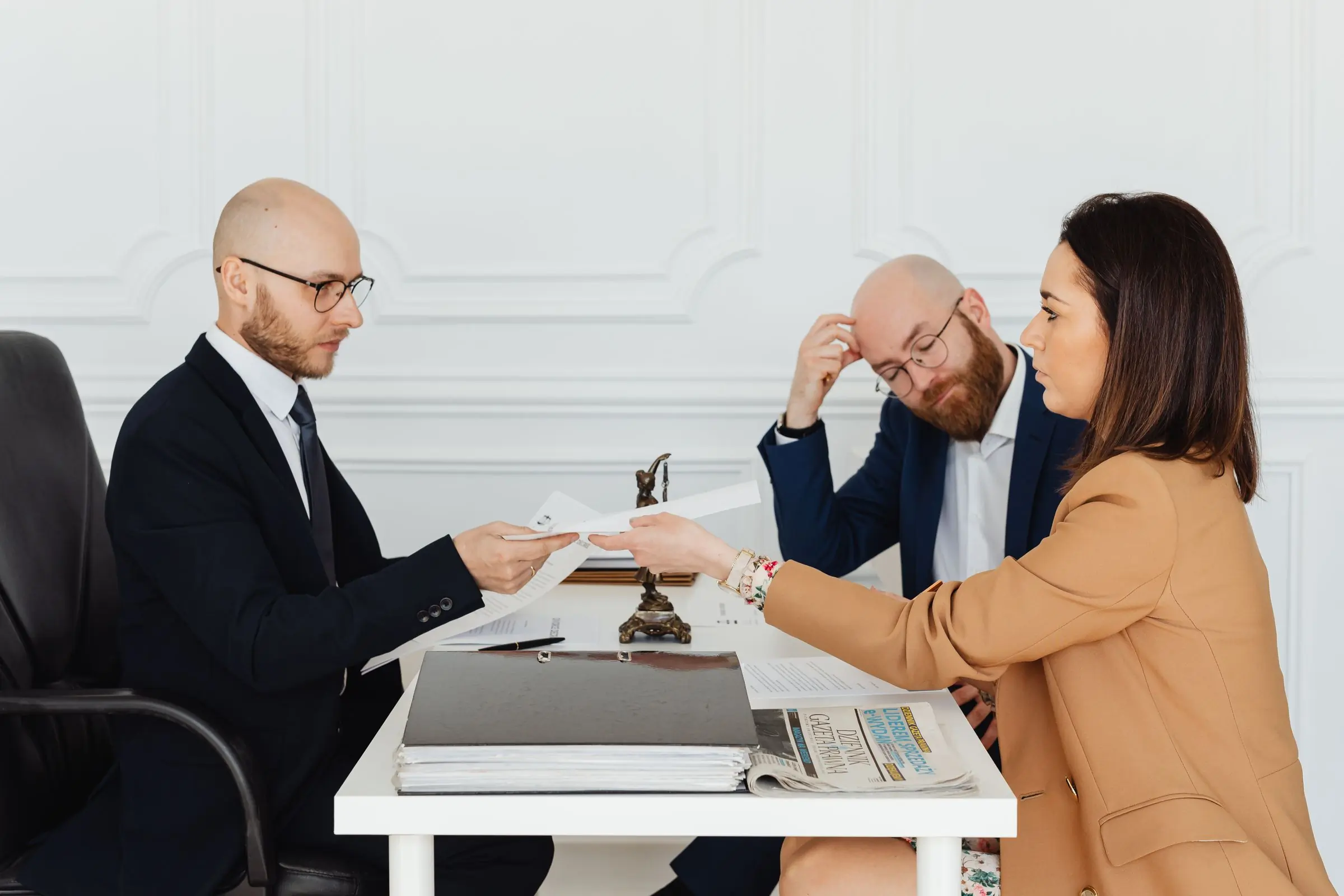An attorney handing signed documents across the table to two clients