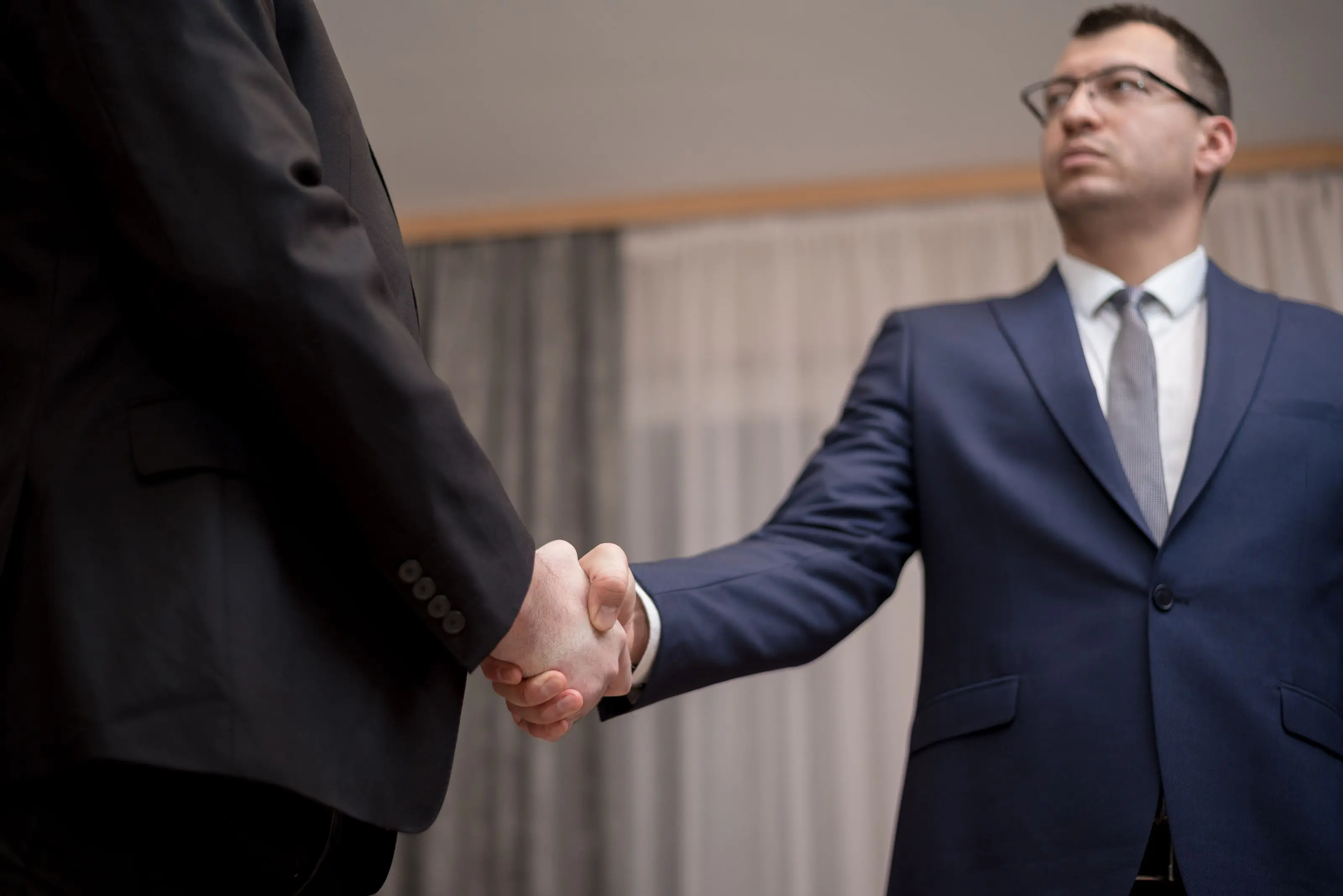 Two attorneys shaking hands at the close of a client meeting