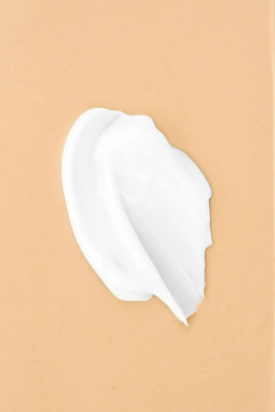 A swatch of white cream swiped across a flat tan surface