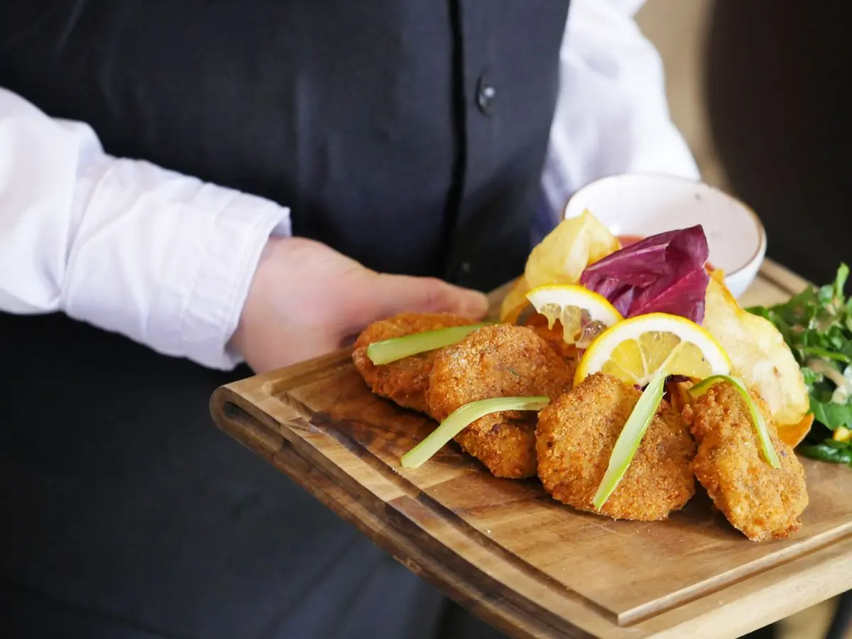 A wooden board of small plates going out to a table
