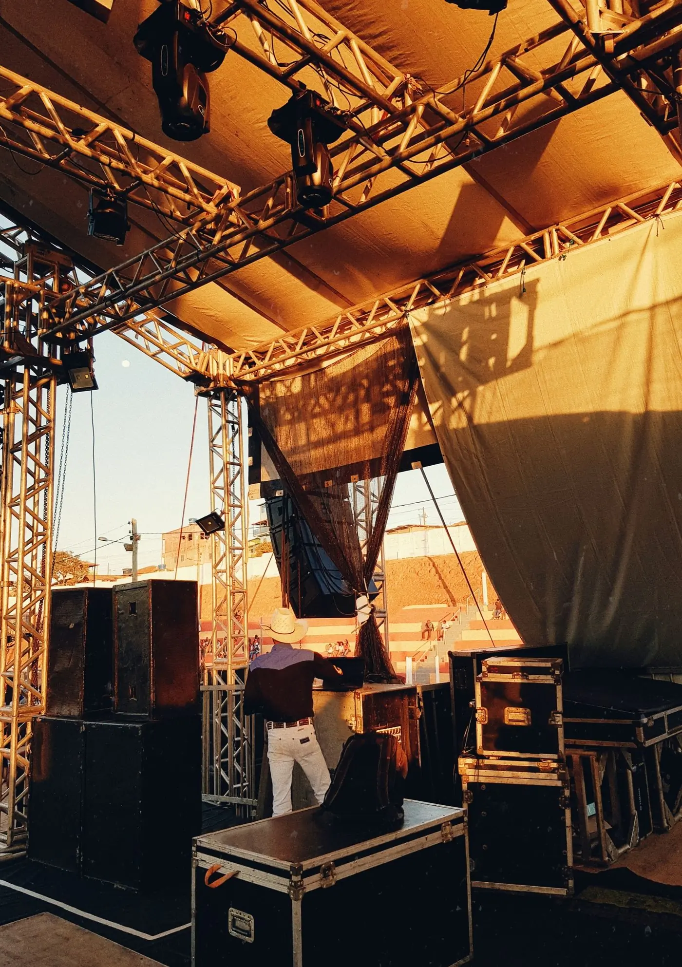 A festival stage being rigged against an evening sky