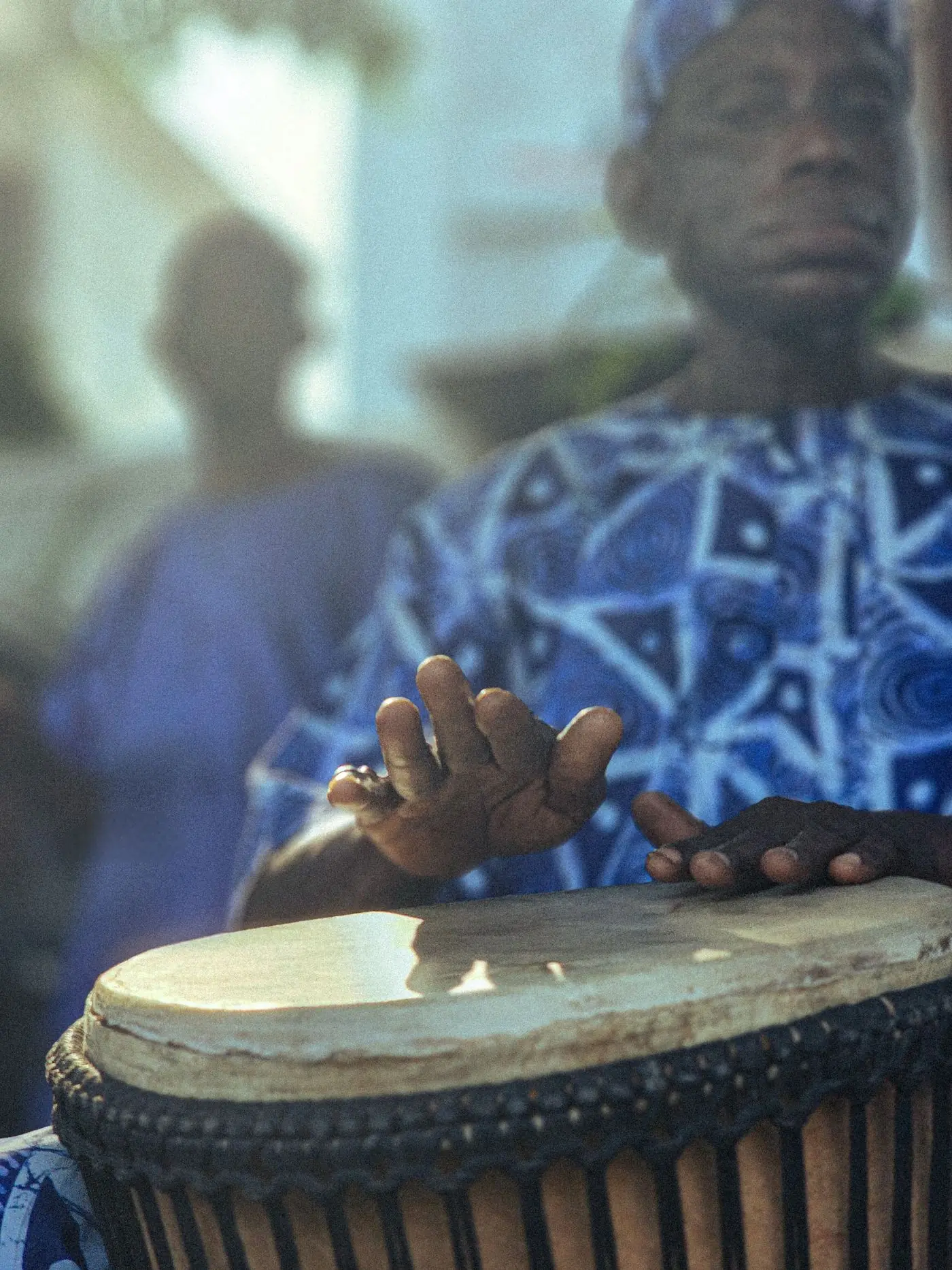 Hands playing a traditional drum in patterned cloth