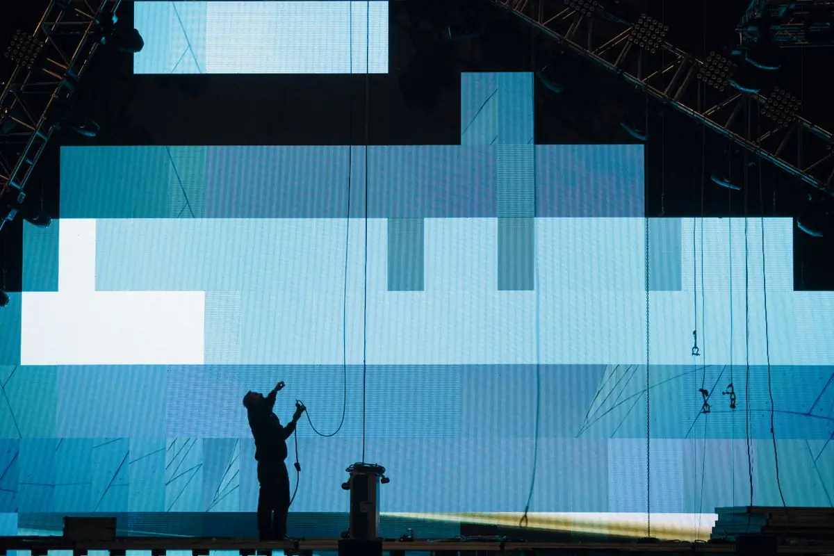 A crew member installing a screen on a festival stage