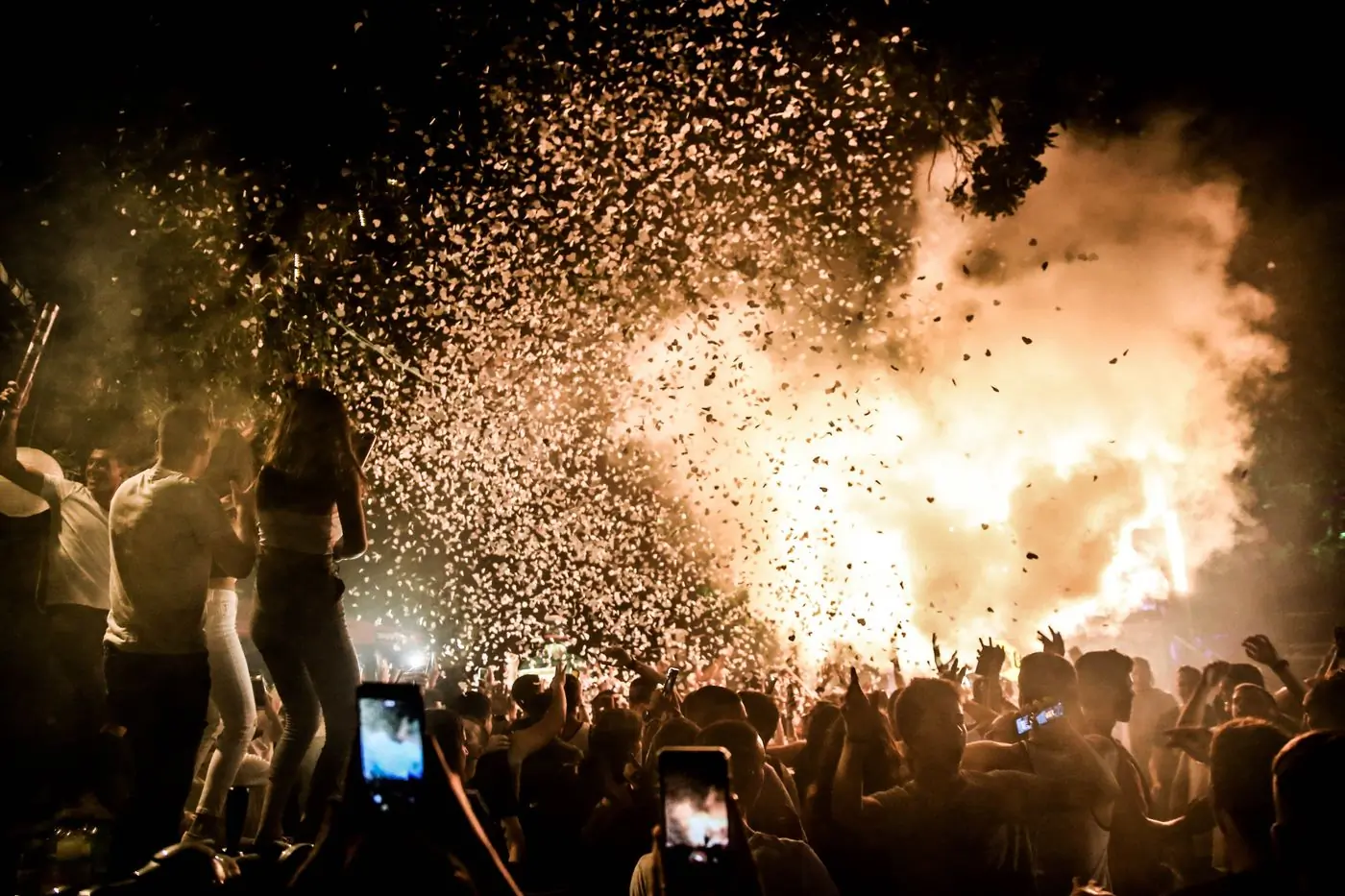 Sparks and lights bursting above a night-time festival crowd
