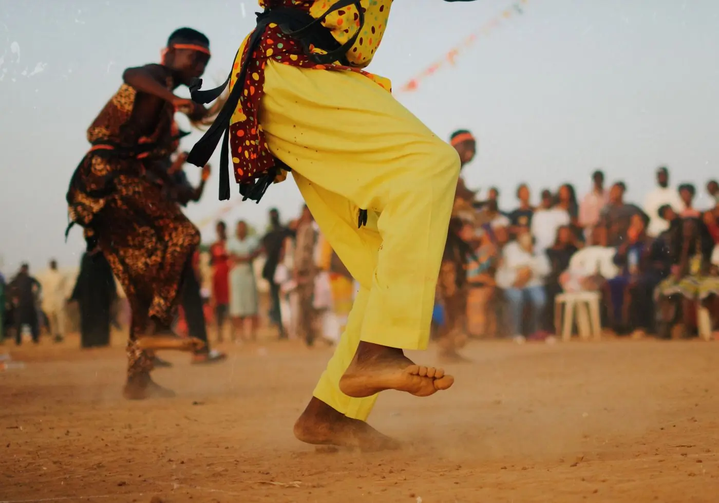 A dancer in yellow trousers mid-step in front of a festival crowd