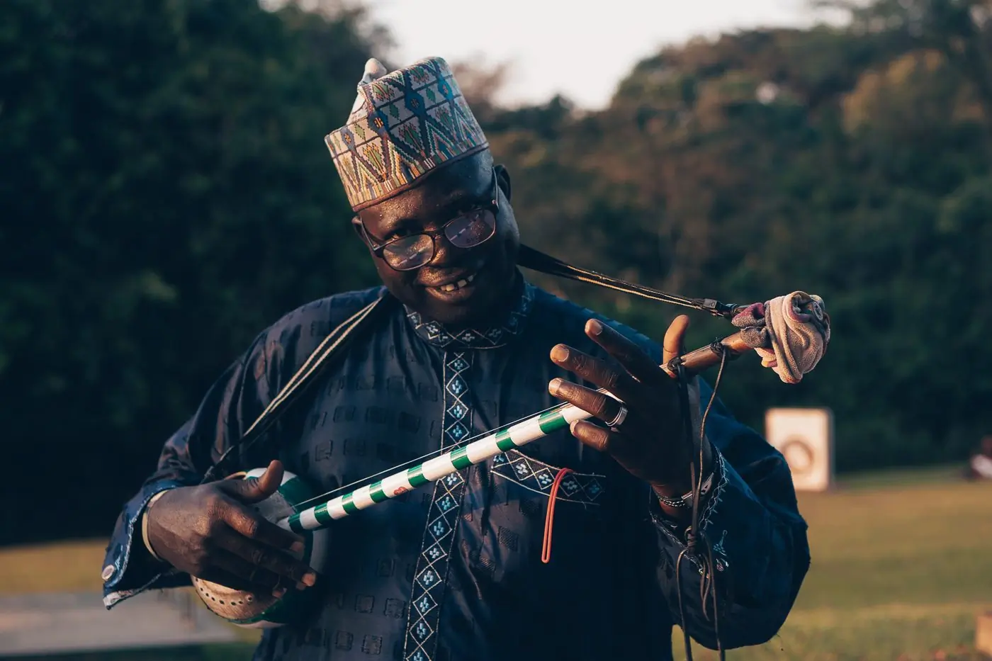 A musician in a hat playing a traditional stringed instrument outdoors