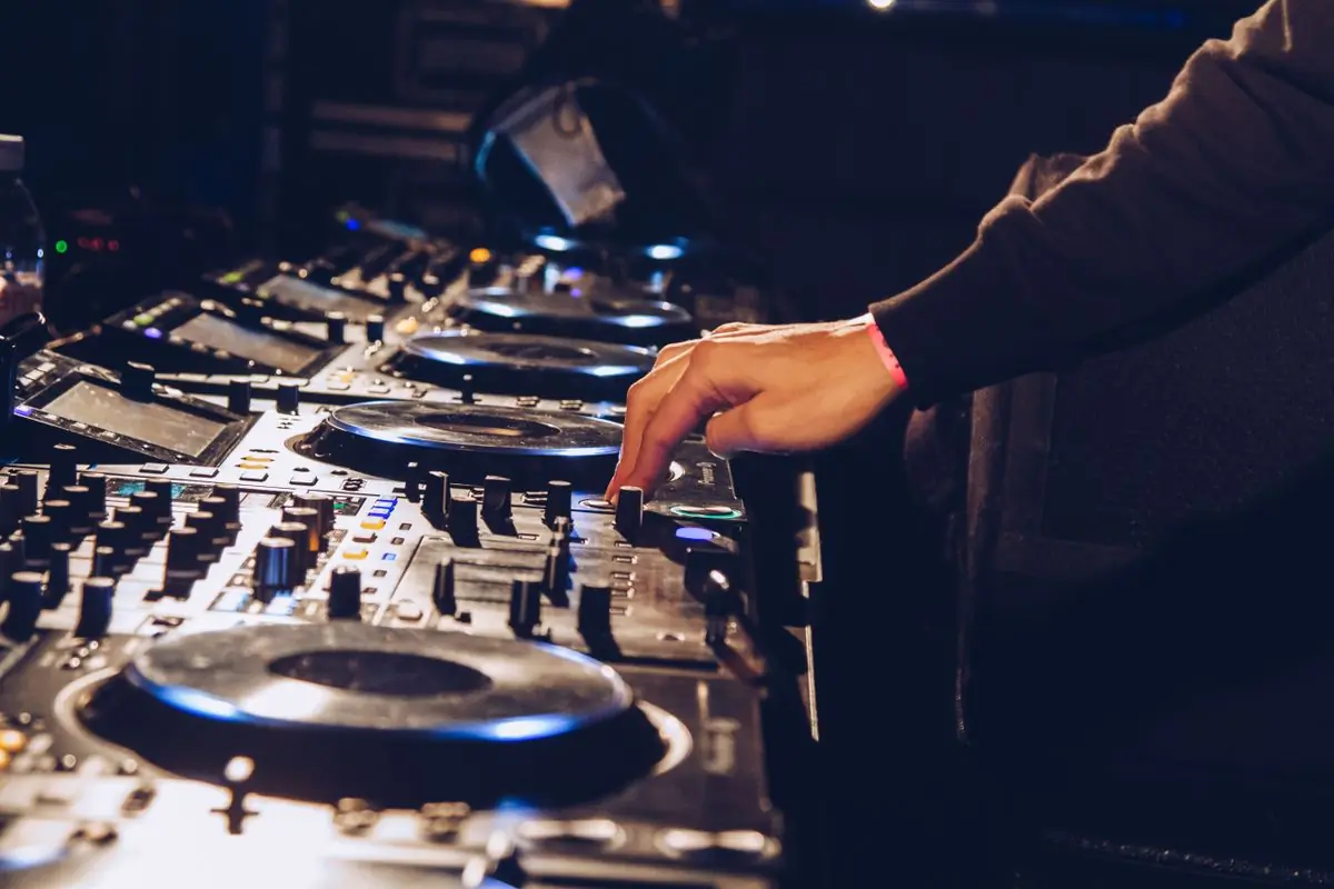 A DJ's hands working a mixing console