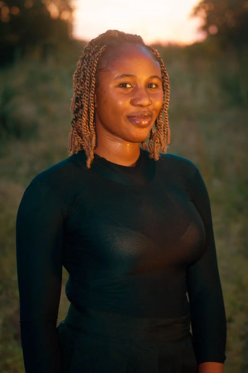 A woman with braided hair photographed outdoors at sunset