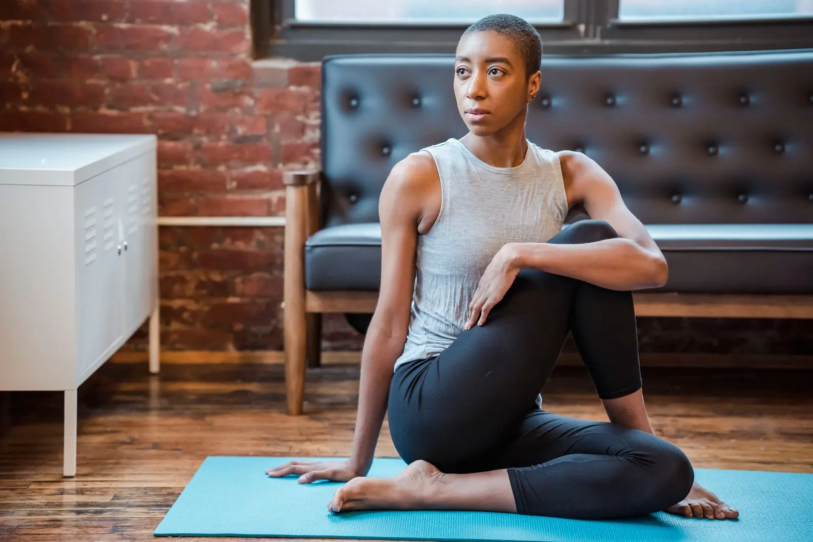 A woman holding a seated spinal twist on a mat in a warm, sunlit room