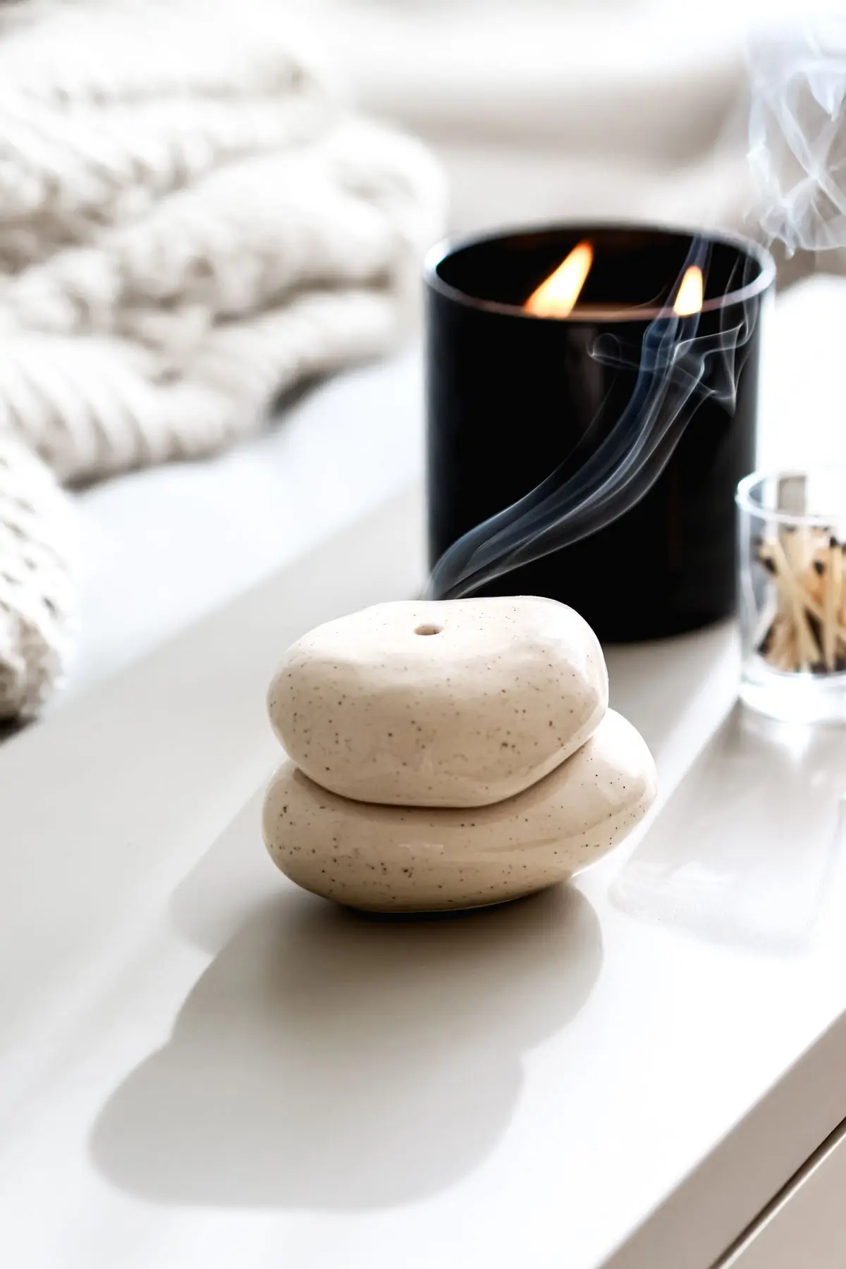 Three smooth river stones stacked on a pale surface