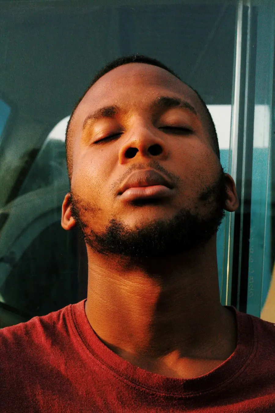 A man with his eyes closed, head tilted back, in warm light