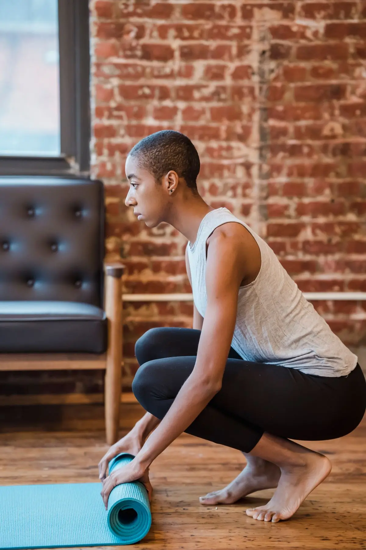 A woman unrolling a yoga mat in a bright studio