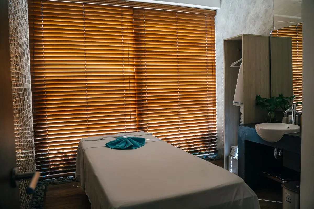 A treatment table beside a window with warm wooden blinds