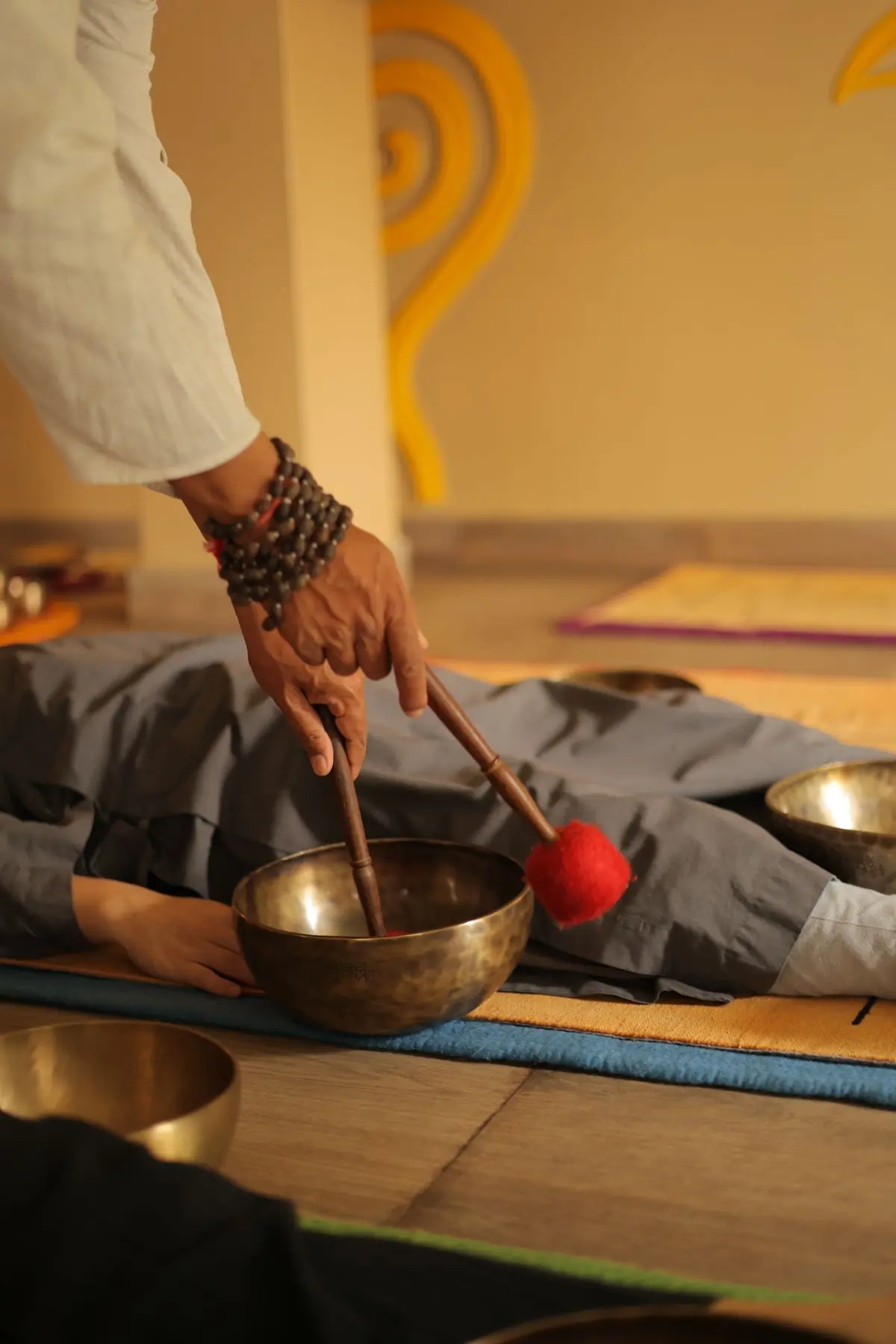 A hand striking a Tibetan singing bowl with a felt mallet