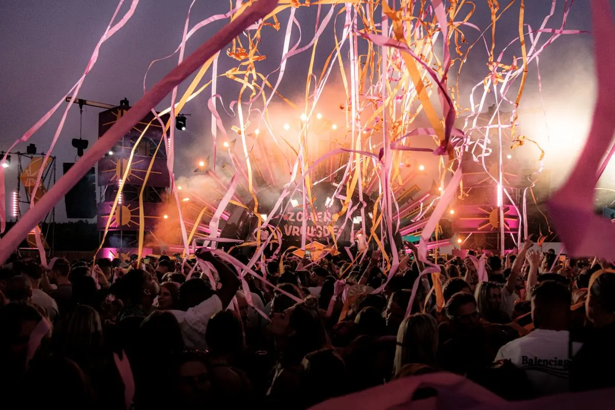 Streamers and confetti over a festival crowd at golden hour
