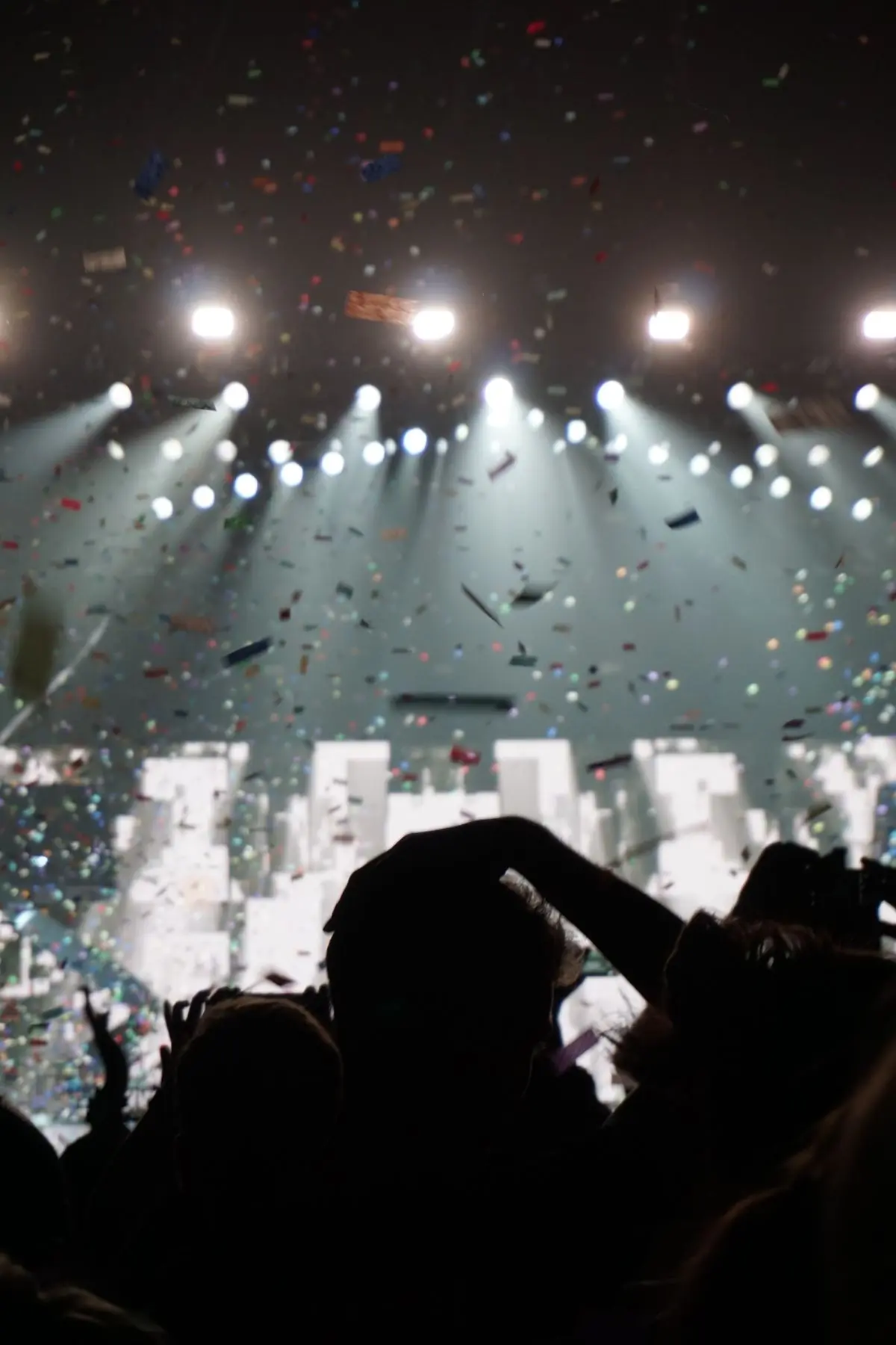 Confetti falling through white stage lights over an audience