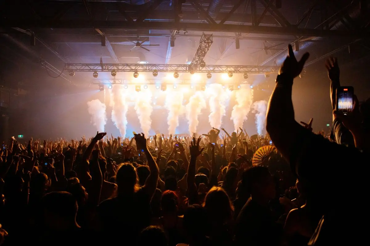 A crowd with hands raised in warm light in front of the main stage