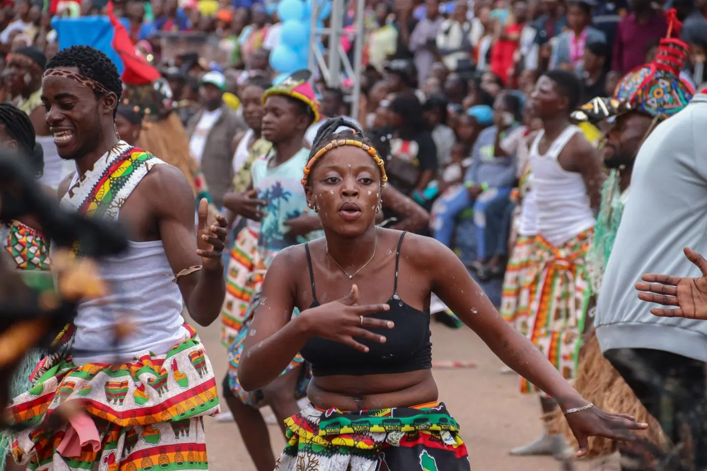 A dense crowd dancing in daylight at an outdoor celebration
