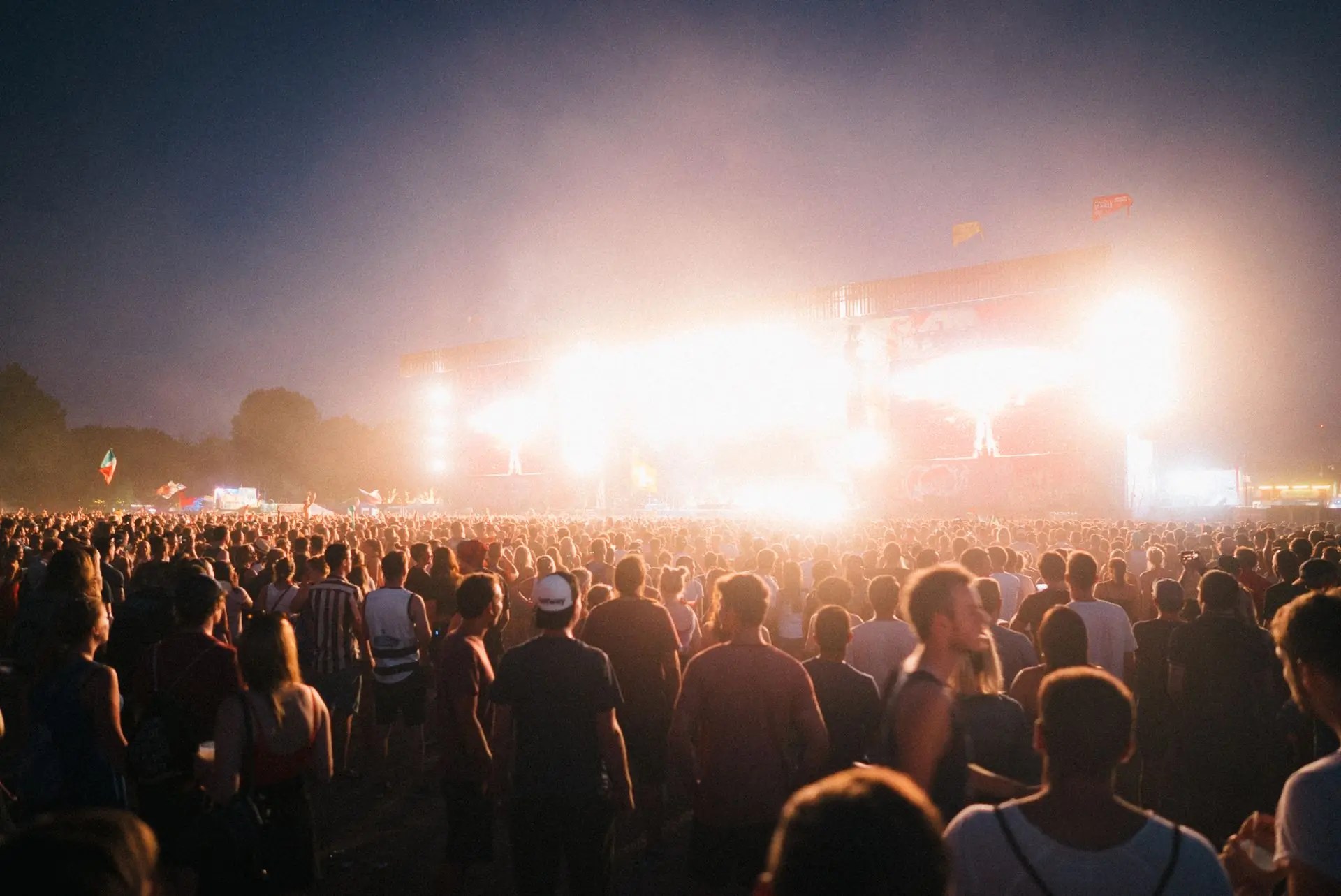 The main stage at dusk with the crowd filling the field in front of it