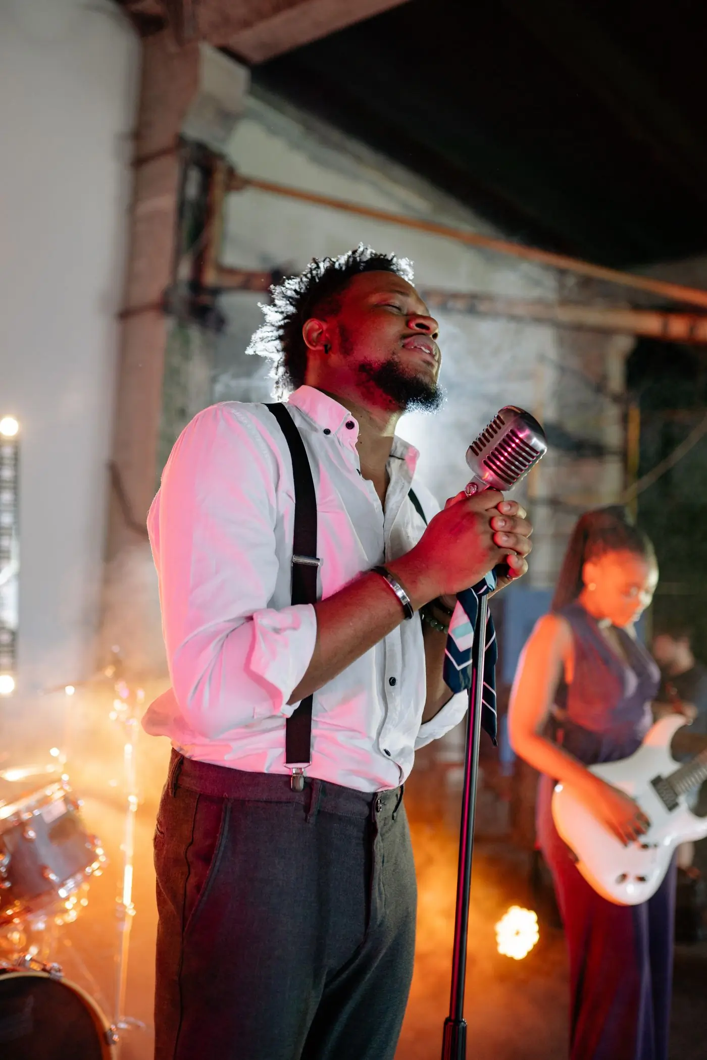 A vocalist and band mid-song under warm stage light