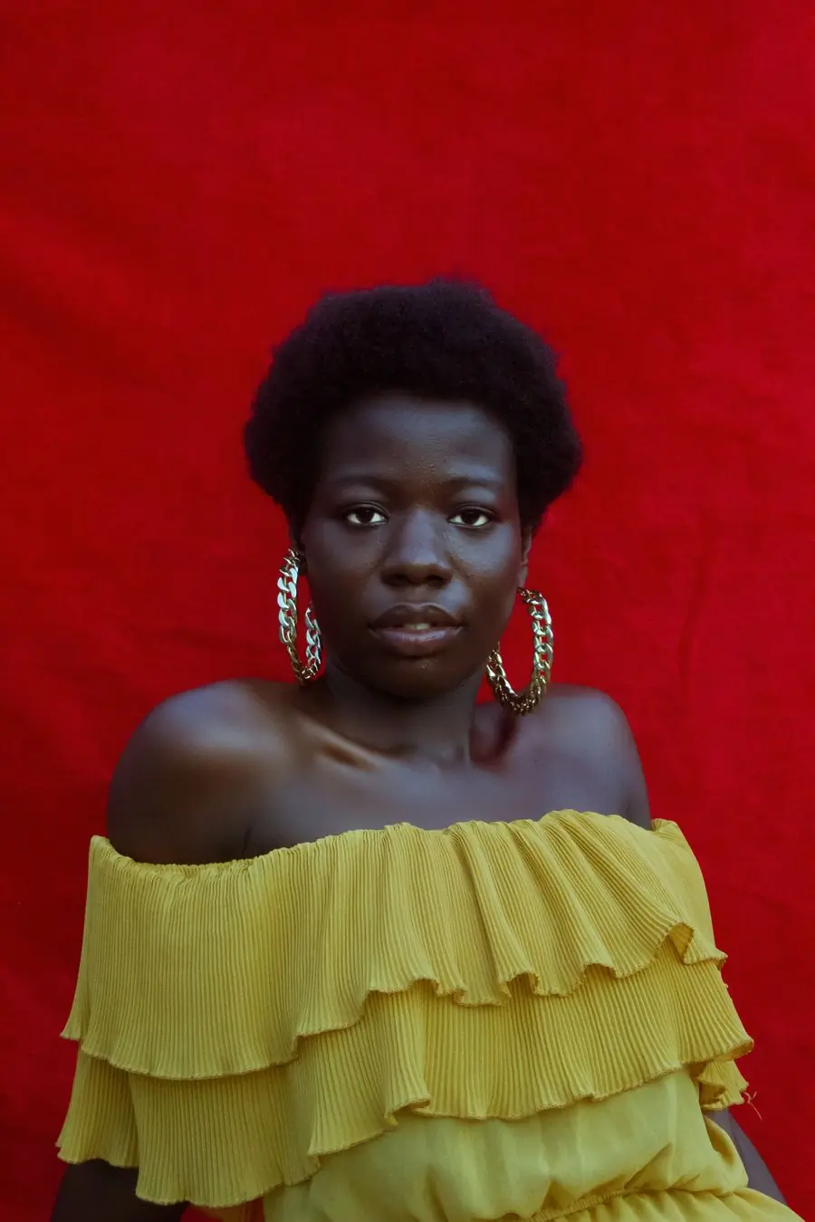 A singer in hoop earrings against a deep red backdrop