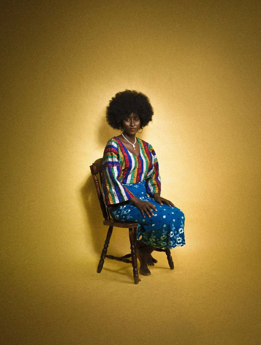 A singer seated in patterned dress against a gold backdrop