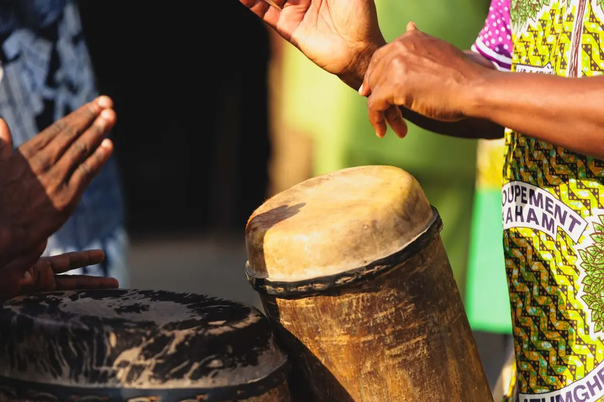 Hands mid-strike on a set of traditional drums in patterned cloth