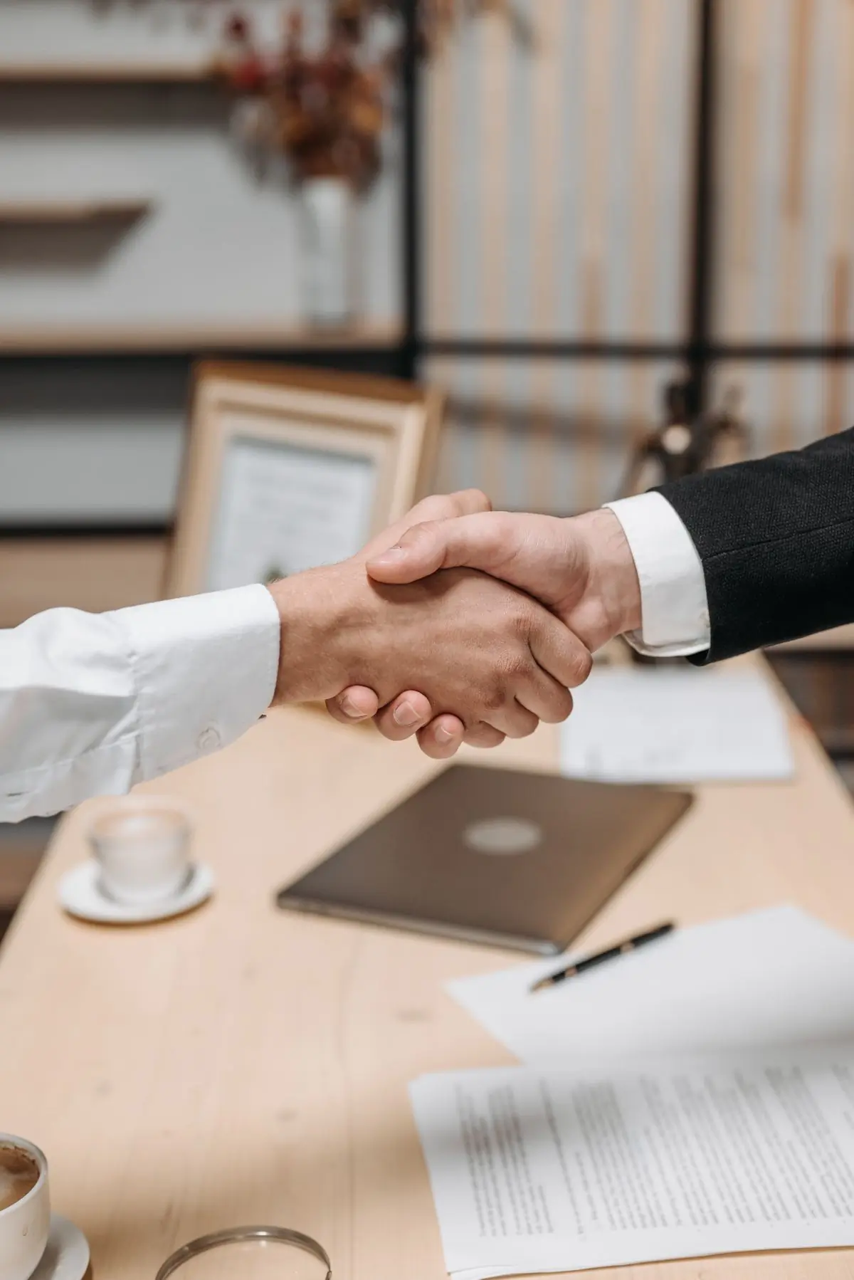 Two people shaking hands over a signed agreement