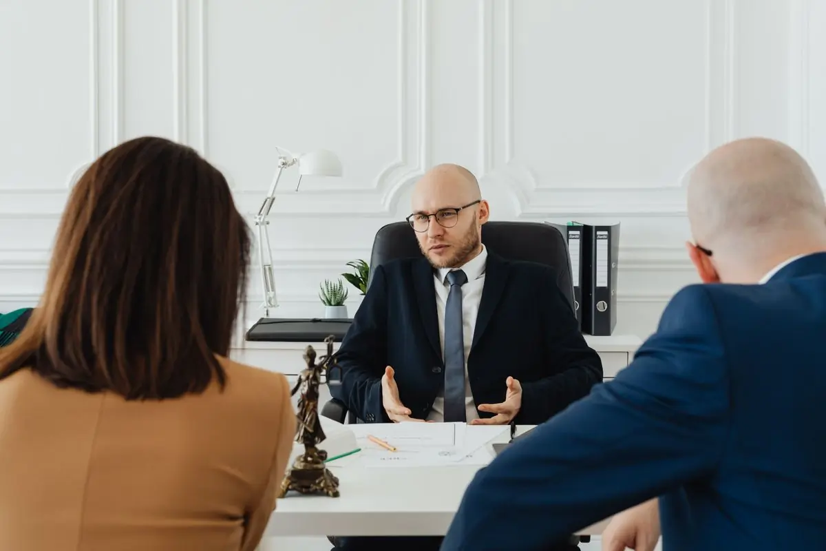 An advocate meeting two clients across his desk