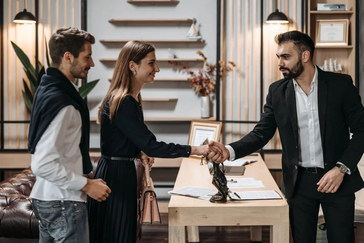 A couple shaking hands with their advocate over a completed sale