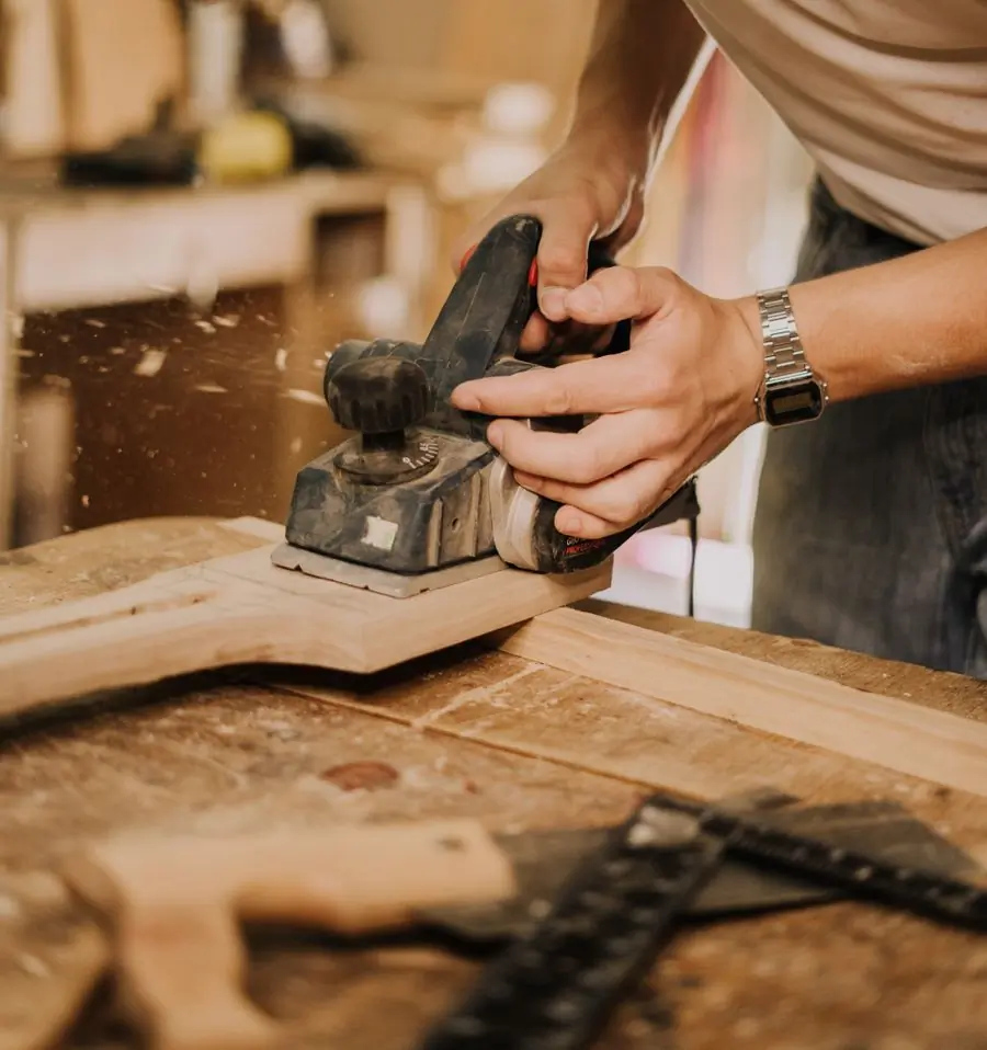 A carpenter working a plank flat with a hand plane