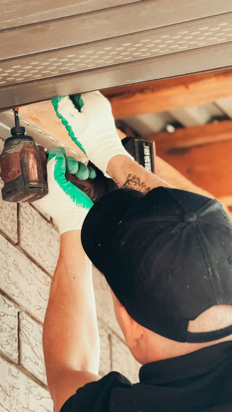 An electrician fitting an outdoor light under a roof overhang