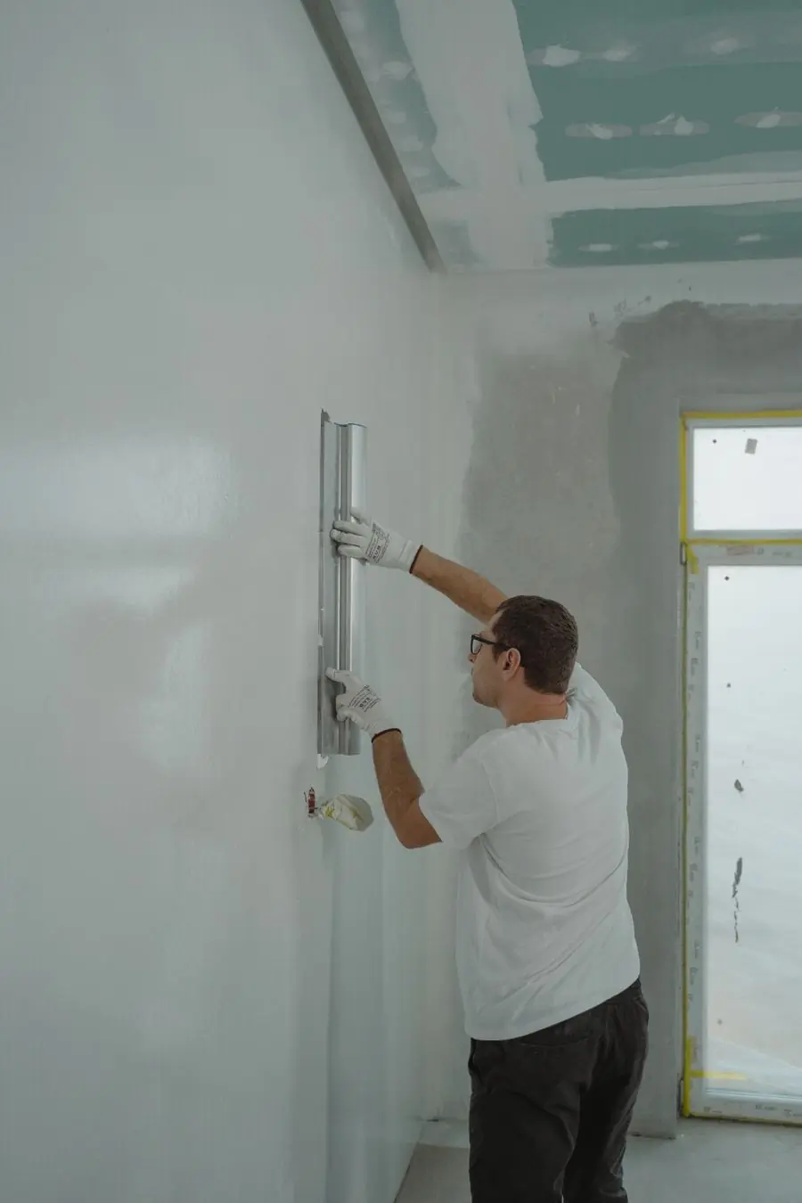 A decorator cutting in the second coat on a bedroom wall